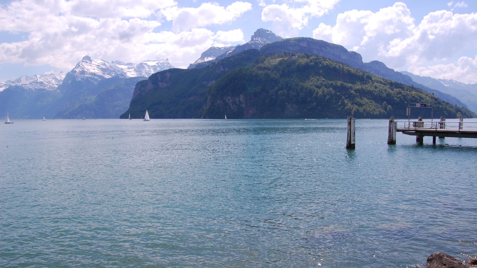 Blick vom Ufer auf den See, Schiffsteg und Berge