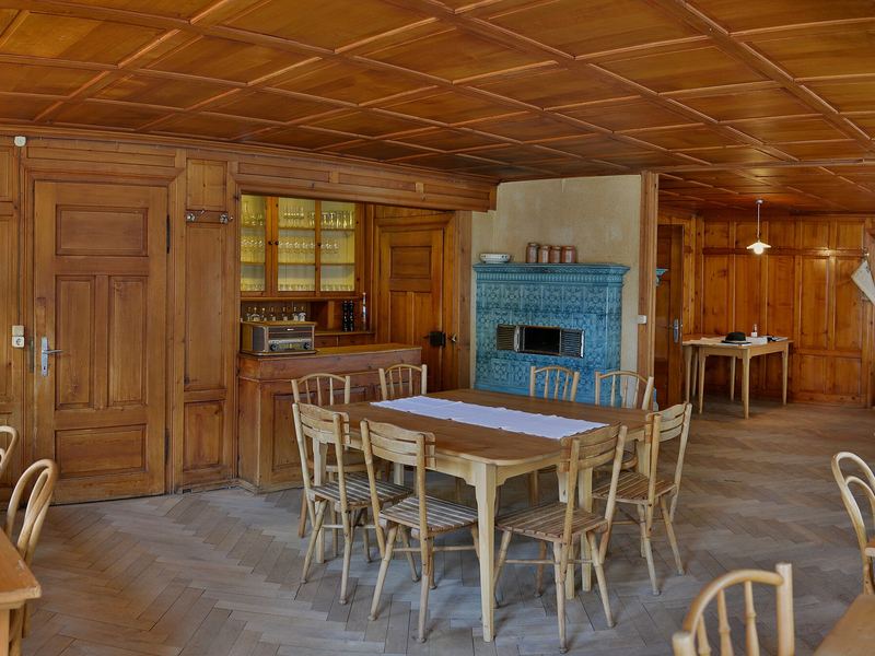 Holzgetäferte Gaststube mit langen Tischen und Kachelofen